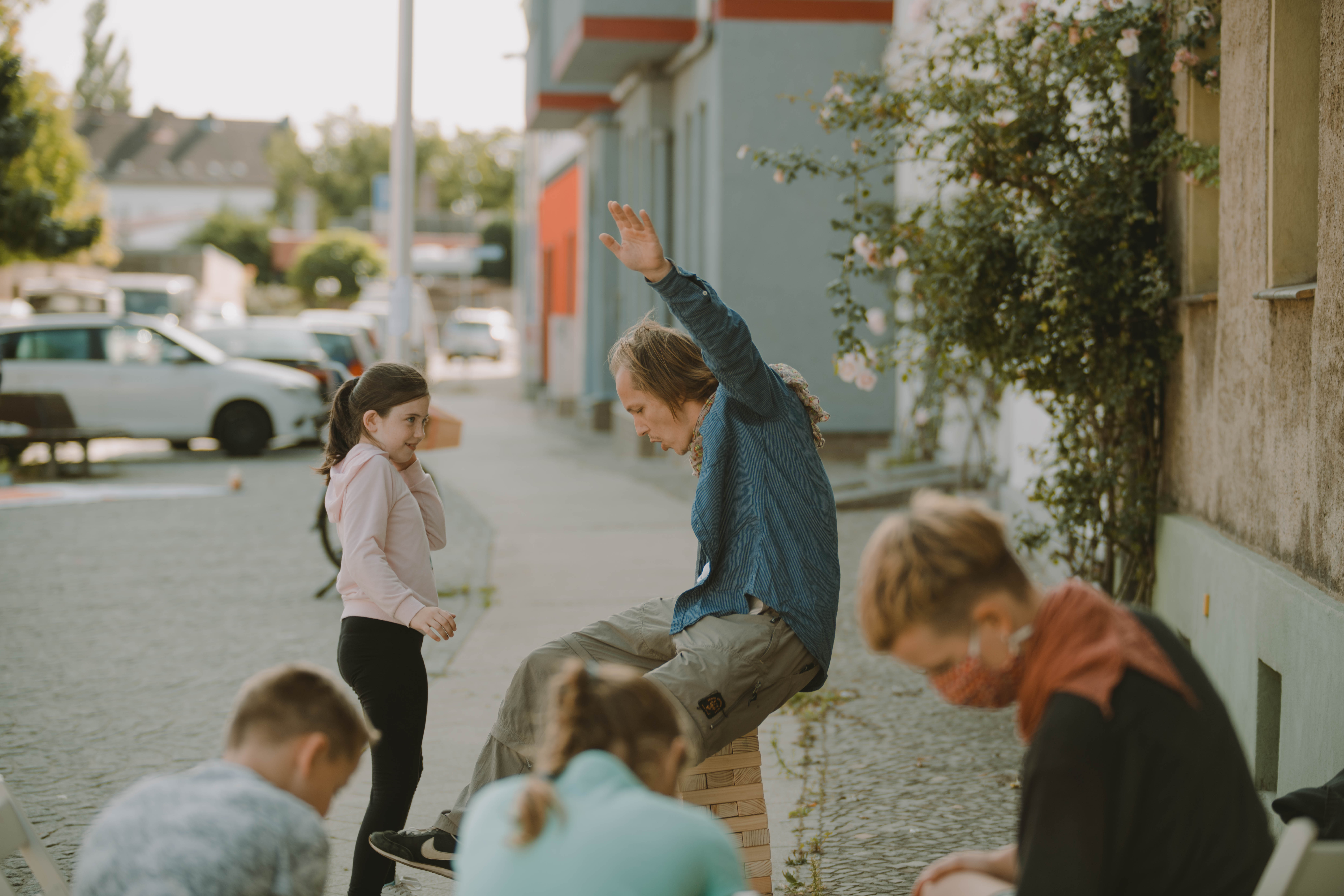 Ein Kind schaut einer Person beim Balancieren zu, Im Vordergrund sitzen mehr Menschen und gucken etwas auf dem Boden an.