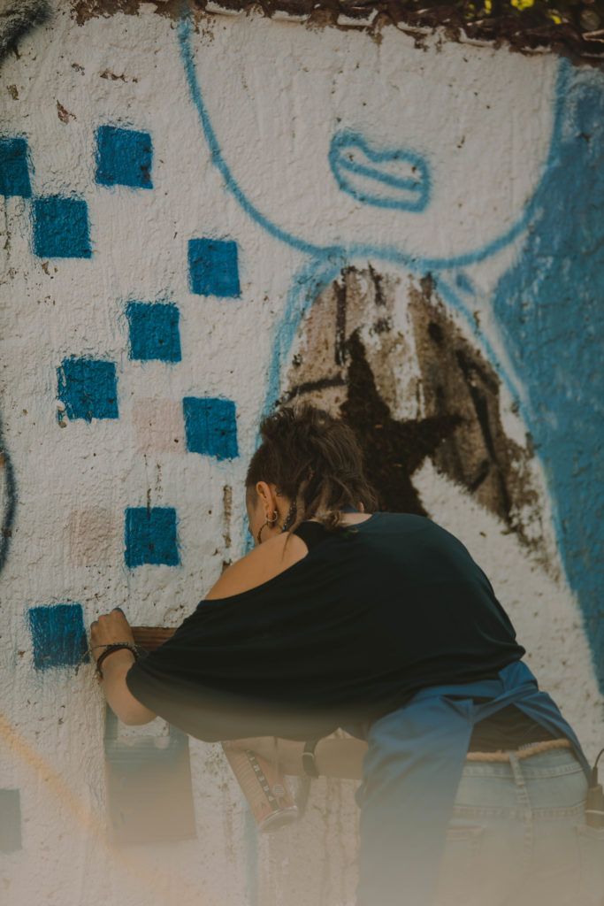 Eine Person besprüht eine Mauer mit blauen Quadraten. Dies ist im Rahmen eines Workshops beim KIEZ Kunst.Aktions.Tag 2020 entstanden.